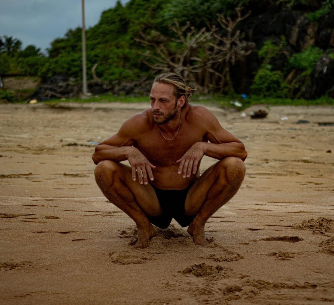 Deep resting squat on a black sand beach